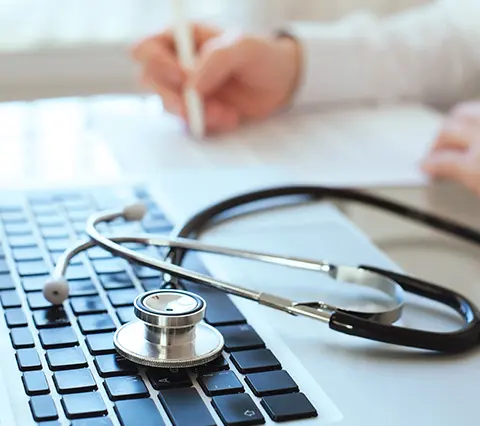 Precios Colonoscopia Bogotá | estetoscopio sobre teclado de laptop con manos de médico escribiendo en documento, precios colonoscopia Bogotá