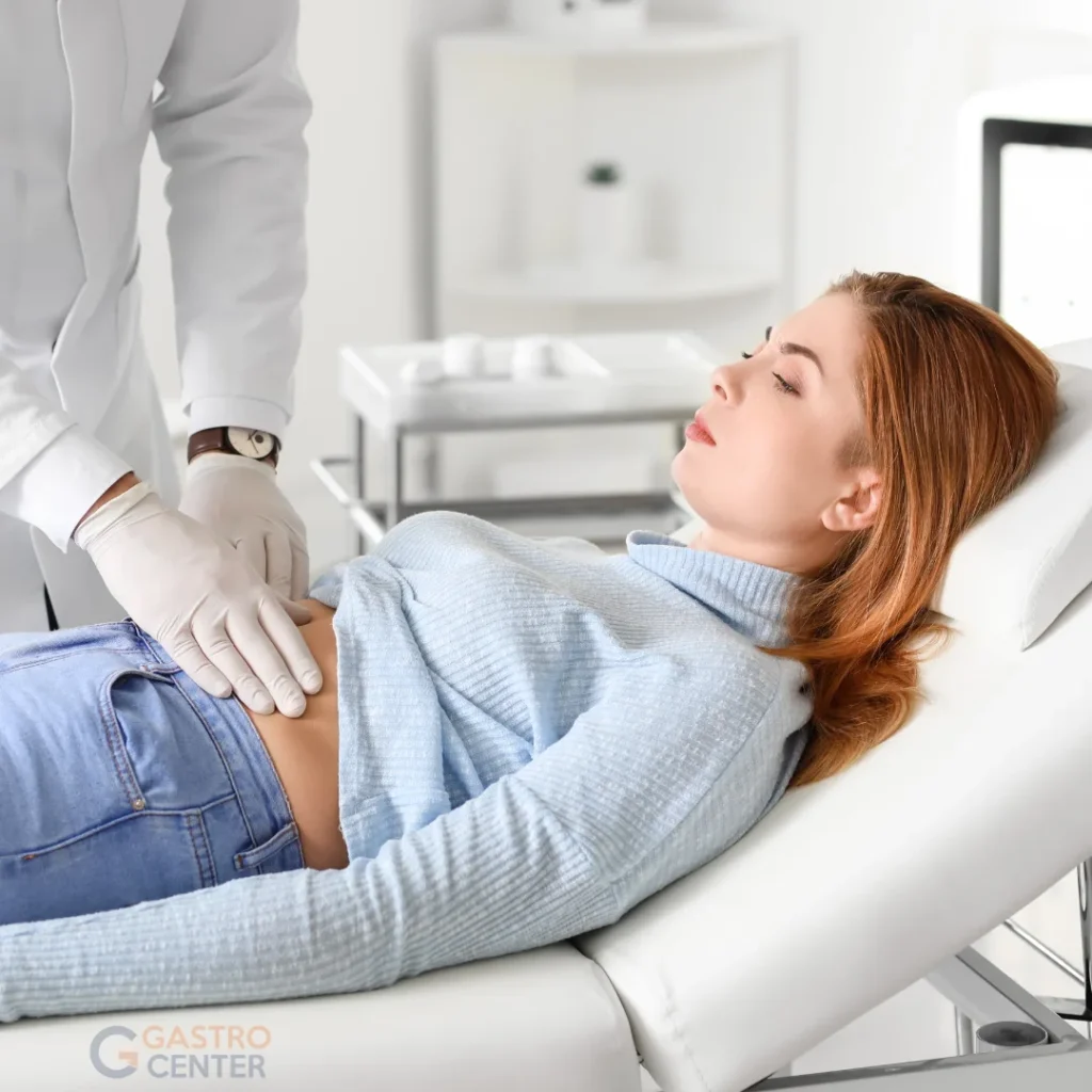médico gastroenterólogo palpando el abdomen de una paciente recostada en camilla clínica en Bogotá