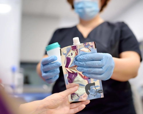 Paciente recibiendo el kit para Test de Aliento para Helicobacter Pylori de una enfermera con guantes